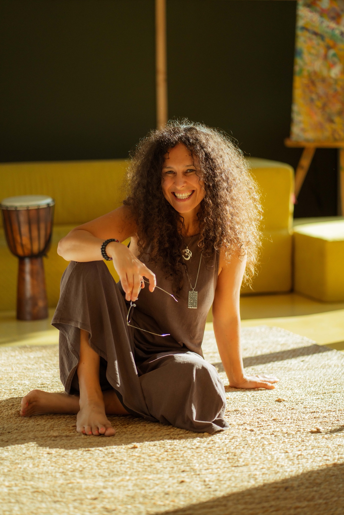 Andrea Varadi Goia sitting on a rug in warm sunlight, smiling