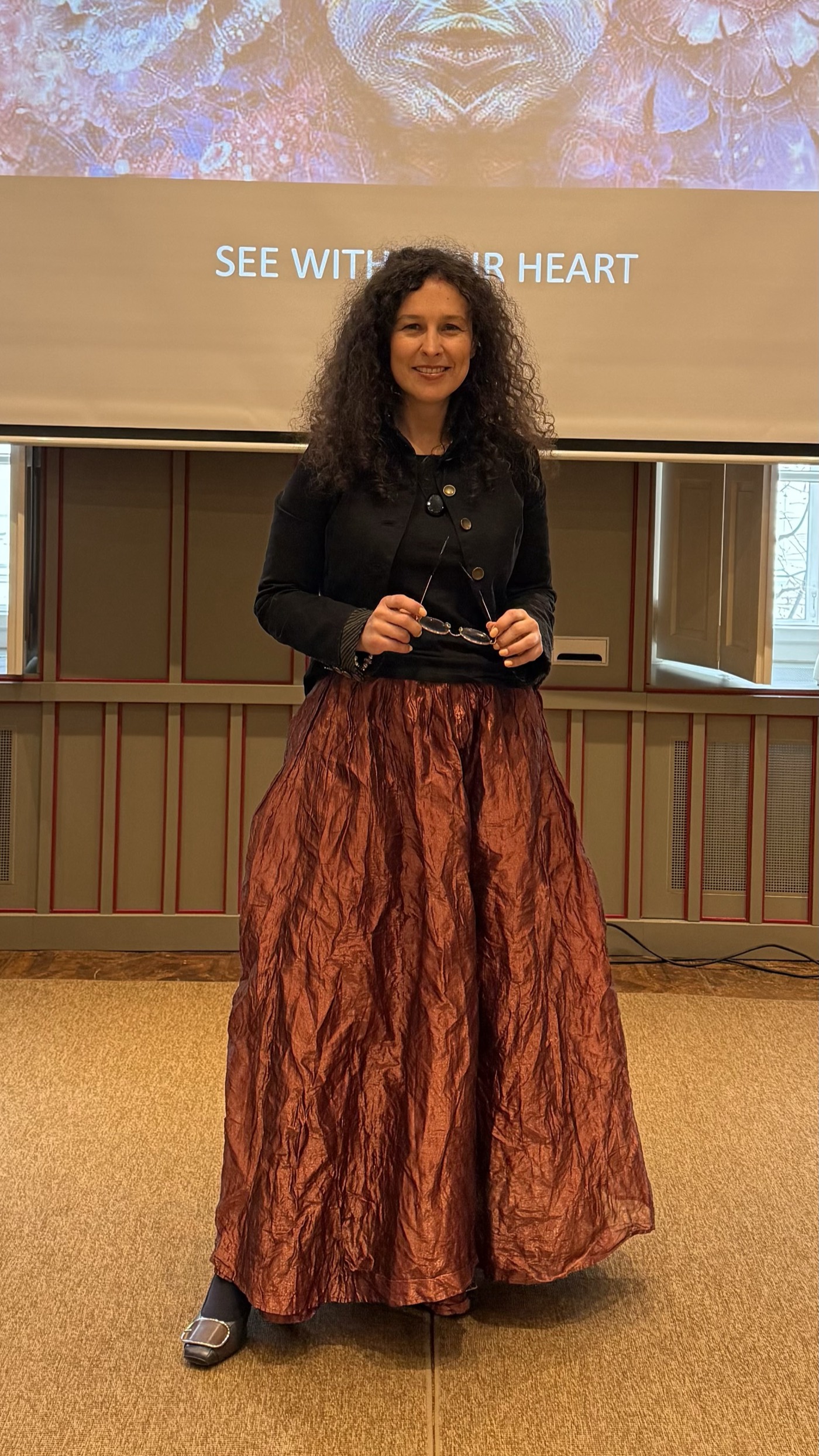 Andrea Varadi Goia standing in front of the See With Your Heart screen
