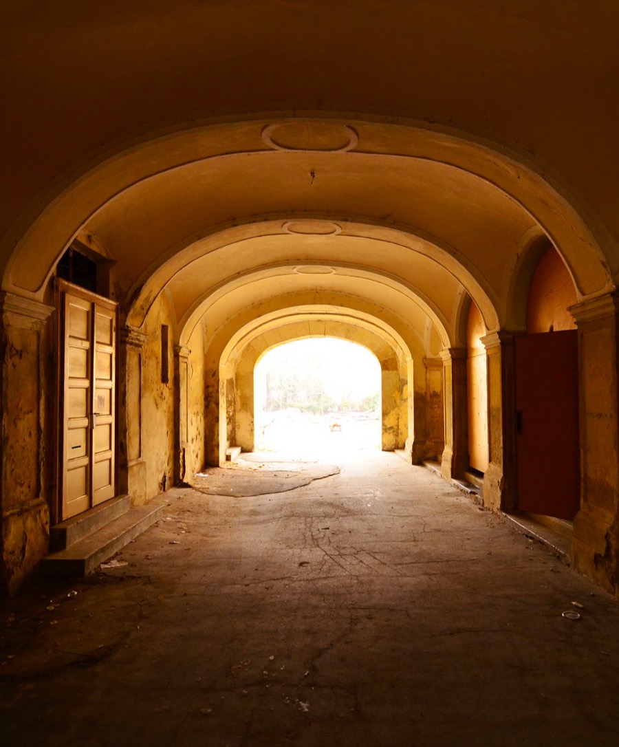 A sunlit stone archway opening onto bright light at the end of the passage
