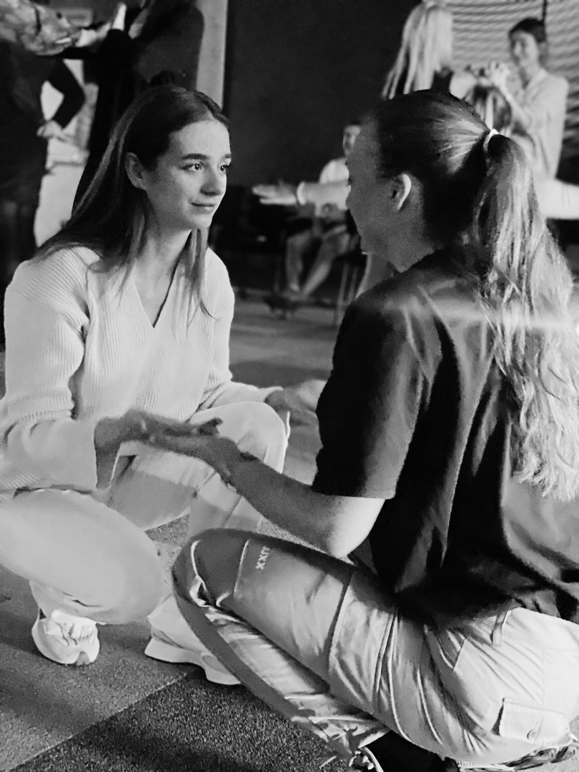 Two participants sitting on the floor, one listening as the other speaks