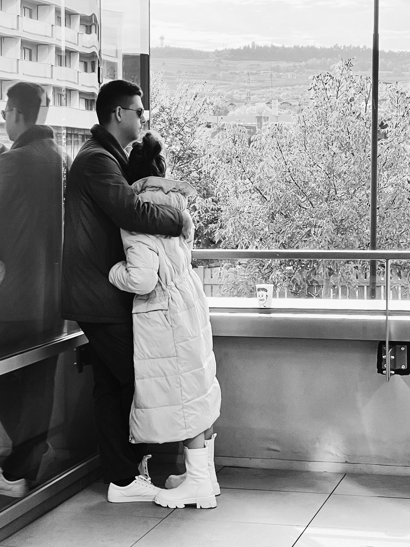 Two participants embracing by a window looking out over the city