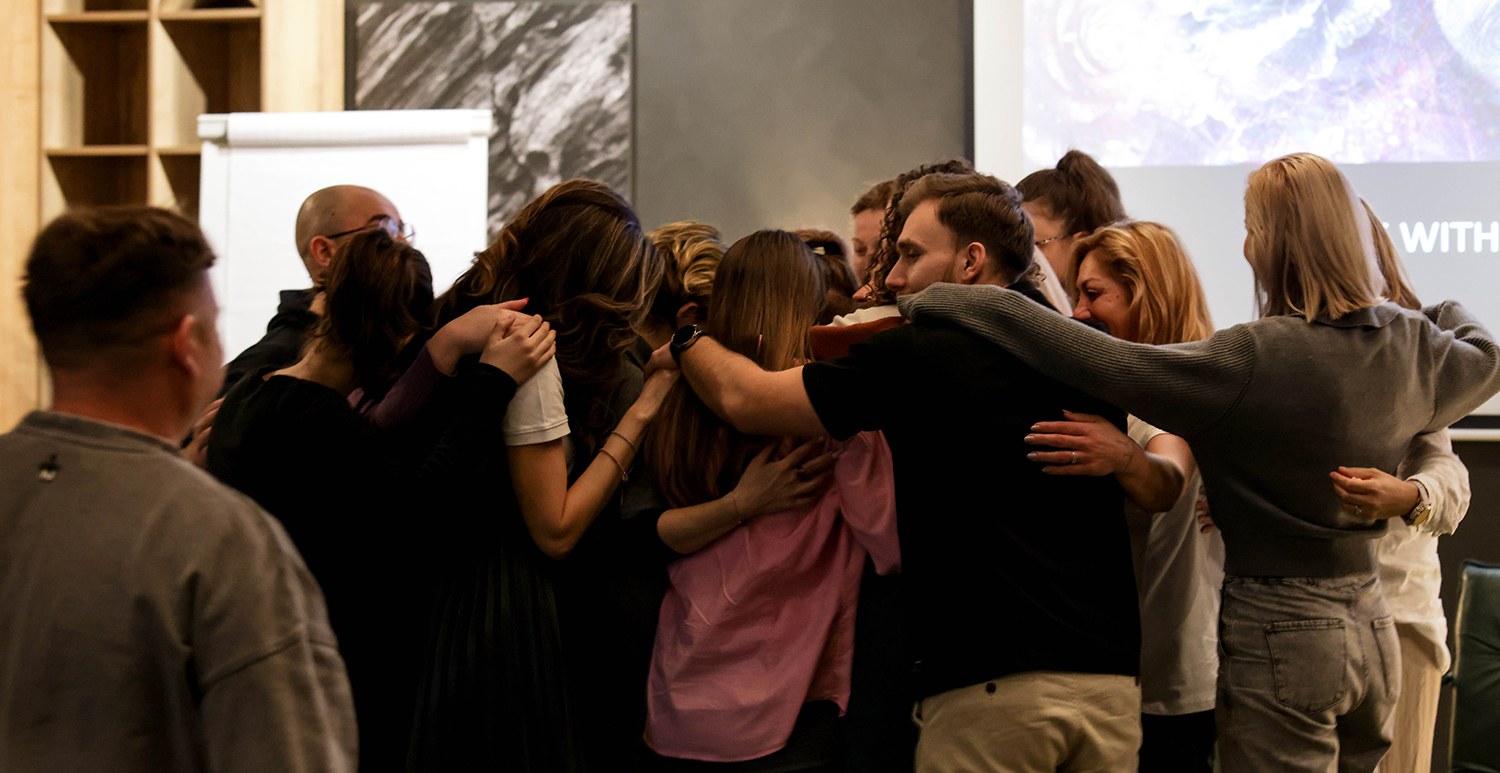 A group of participants hugging at the workshop